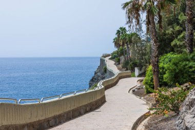 Atlantik Okyanusu 'nun mavi yüzeyi üzerinde, ufukta bulutsuz mavi gökyüzü ile birleşen bir uçurumun kenarındaki inanılmaz güzel bir patika manzarası. İspanya.