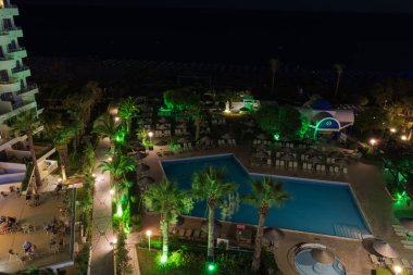 Rodos adasındaki otelin büyüleyici gece manzarası, renkli ışıklarla, karanlık arka plana karşı büyüleyici bir sahne yaratıyor. Rodos, Yunanistan.