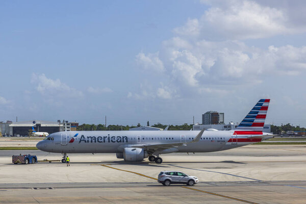 Самолеты American Airlines размещены на взлетно-посадочной полосе, управляемые тяговым трактором для взлёта. Майами. США. 
