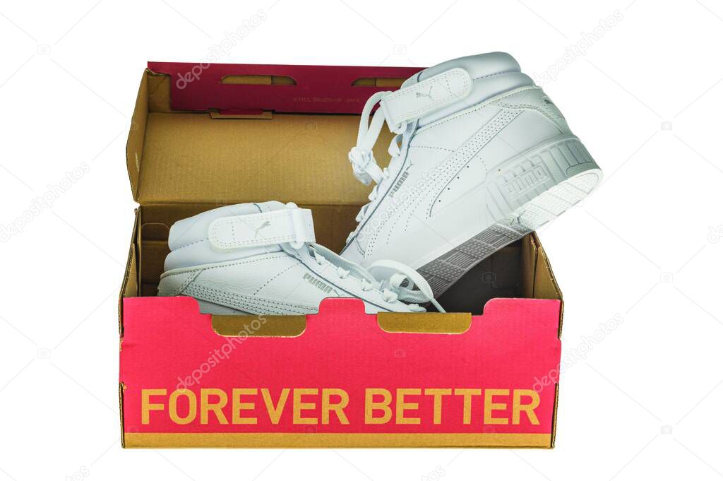 Close-up of white high-top Puma sneakers lying inside an open red box isolated on white background.