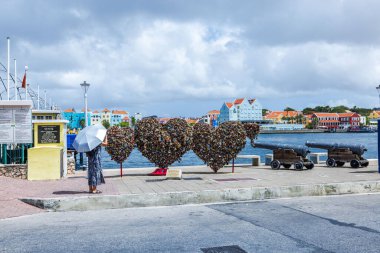 Beautiful view of three heart symbols installed on St. Anna Bay promenade adorned with hanging locks on island of Curacao.  clipart