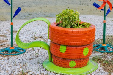 View of vibrant flowerbed designed like coffee cup, made from old, unusable car tires, filled with tropical plants. Curacao. clipart