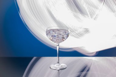 Bardakta buz küpleri olan, mavi-beyaz arka planda izole edilmiş bir içeceğin yakın görüntüsü..