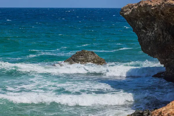 Aruba adasının kayalık sahillerindeki Karayip dalgalarının manzarası.