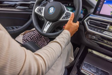 BMW iX3M elektrikli arabanın direksiyonundaki bir kadının yakın çekim görüntüsü.. 