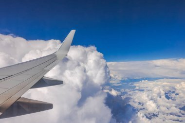 Uçuş sırasında beyaz bulutlu mavi gökyüzünün uçak penceresinden güzel bir manzara..