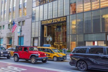 New York 'ta Trump Tower' ın muhteşem girişinin güzel bir manzarası var. Kalabalık sokak trafiği ve yukarıda dalgalanan Amerikan bayrağı çerçeveli. - New York. ABD.