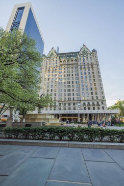 The Plaza Otel 'in gökdeleninin güzel bir manzarası. İnsanlar Beşinci Cadde' deki parkta geziniyor. - New York. ABD. 