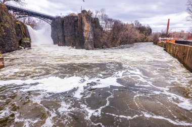 İlkbahar atmosferinde uçurumlarla çevrili Paterson şelalesinin parktaki güzel manzarası güzelliği ve gücüyle etkiler. New Jersey.
