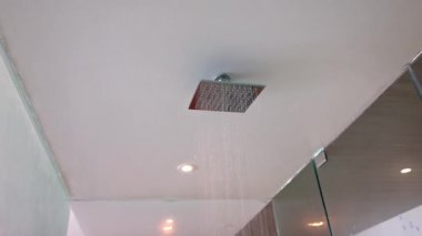 Cam duş kabini ve tropikal yağmurlu duş başlığıyla tavana monte edilmiş geniş duşlu otel odasının yakın görüntüsü. Meksika.