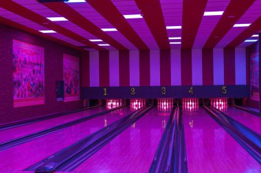 Bowling salonunun içi görünüyor. İğneler yerleştirilmiş ve aydınlatma altında beş şerit var.. 