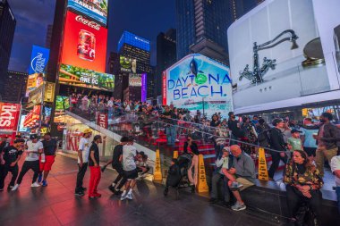 Nighttime view of Times Square with people on the Red Steps against the backdrop of LED advertising panels on the skyscrapers. New York. USA. 