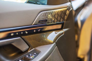 Close-up view of the interior front door panel with carbon trim and Bowers and Wilkins speakers of the BMW i5M electric car.  clipart