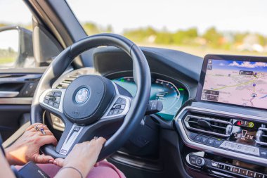 Otoyolda araba sürerken BMW iX3 'ün direksiyonundaki kadın ellerinin yakın çekim görüntüsü. 