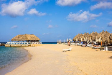 Karayip Denizi 'nin kumlu sahillerinde şemsiyeler ve güneş panzeleriyle dinlenen insanların güzel manzarası.. 
