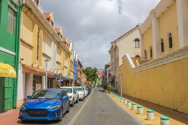 Willemstad, Curacao 'da güneşli bir günde park etmiş arabaların ve sömürge mimarisinin olduğu güzel bir cadde manzarası.. 