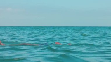 Atlantik Okyanusu 'nun sakin mavi sularında sırtüstü uzanmış mayo giymiş bir kadın. Miami Plajı. ABD.