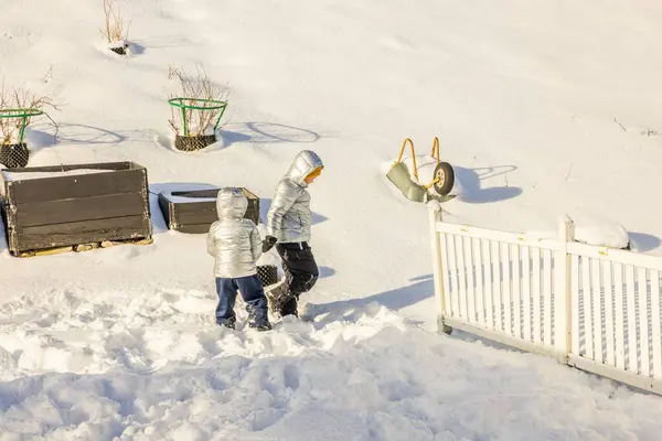 stock image Beautiful winter view of the garden area of a private villa with two boys playing in the snow. Sweden.