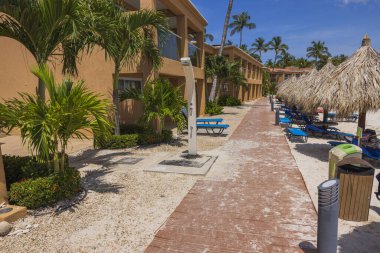 Otelin özel kumlu plajının güzel manzarası. Aruba adasında palmiye yapraklarından yapılmış güneş şemsiyeleri.. 