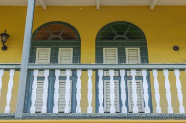 Ahşap balkonları ve kapalı pencere panjurları olan sarı tarihi bir binanın dış görünüşü çok güzel. Curacao. 