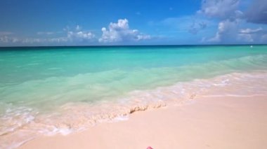 Karayip Denizi 'nin turkuaz sularının güzel manzarası kumlu bir plajda uzanmış dalgalar ayaklarına vuruyor. Aruba.