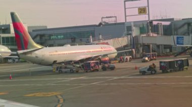 Havaalanındaki pist terminalinde yolcu alımı için yolcu köprülerinin yakınına park edilmiş Delta Havayolları uçaklarının bulunduğu uçağın camından görüntüyü alın. Miami mi? ABD. 