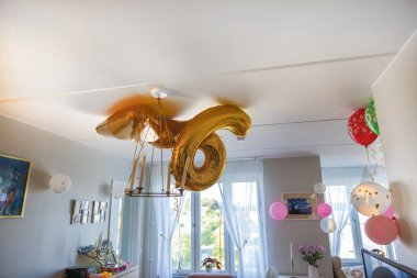 Kutlama için dekore edilmiş odanın yakın görüntüsü, 6 numaralı altın balonlar, renkli balonlar, ve tavandan sarkan çeşitli dekorasyonlar.