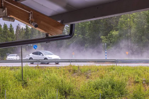 stock image View from under roof at cars on highway on rainy summer day. Sweden.