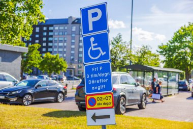 Otoparkta engelli park levhası var. Arkasında arabalar ve binalar var. İsveç. Avrupa. 