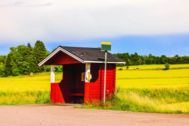 Otoyoldaki otobüs durağının yakın görüntüsü tarıma komşu kırsal kesimde. İsveç. 