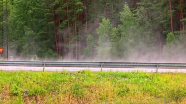 Otoyol manzarası, serinletici yaz yağmurundan sonra yükselen sıcak hava dalgalarıyla, arabalar yolda ilerlerken. İsveç.