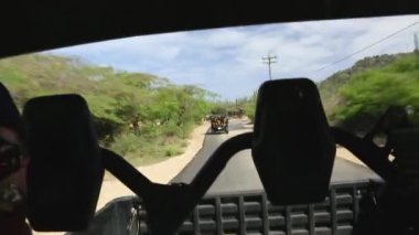 Dağlardaki UTV 'lerin tozlu, bozulmuş şehir asfaltlı yollarından geçişi. Aruba.