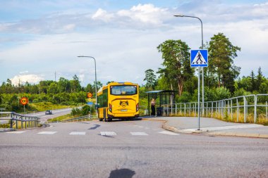 Otobüs durağındaki sarı otobüs, yaya geçidi tabelası ve otobüsten yeni inmiş bir kız.. 