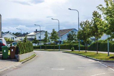 Bulutlu bir günde, modern evler, ağaçlar ve park edilmiş arabalarla İsveç 'in banliyölerinde bir yerleşim yeri..