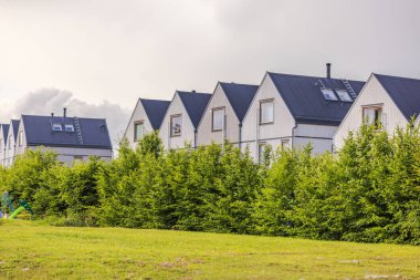 Çitlerle çevrili kozalaklı ağaçlarla çevrili bir Avrupa köyündeki modern, üniformalı ahşap villaların manzarası doğayı çağdaş yaşamla harmanlıyor. İsveç.