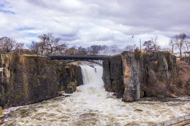 New Jersey 'de bahar manzarası. Paterson Şelaleleri Passaic nehrinden aşağı dökülüyor. Dağ manzarası ve bulutlu gökyüzü çerçeveli..