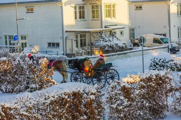 stock image Christmas scene with festive decorations and snow-covered streets showing horse-drawn carriage with Santa in snowy residential neighborhood. 