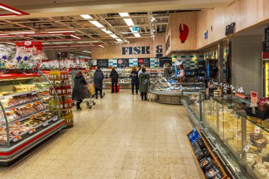 Noel dekore edilmiş hipermarket balık departmanı. Müşteriler dondurulmuş vitrinlerden deniz ürünleri seçiyor.. 