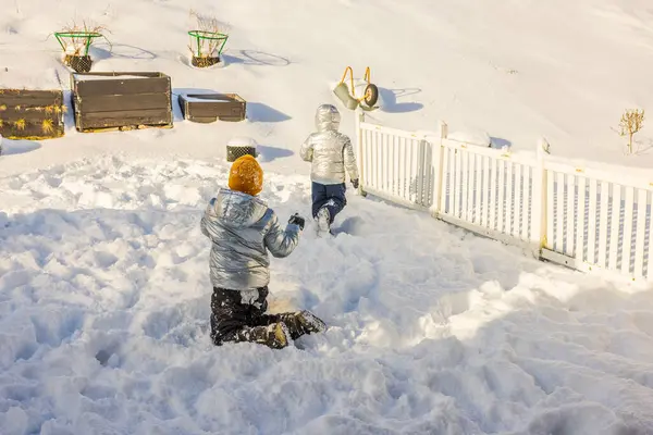 stock image Close-up of two children playing with snowballs in backyard of villa on sunny frosty winter day. Sweden.