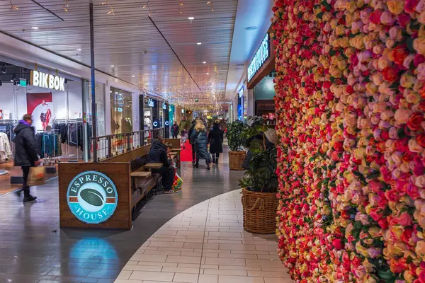 stock image Christmas-decorated hypermarket hallway with boutiques, colorful rose wall, and Espresso House sign, with shoppers browsing and shopping. 