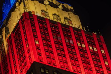 Empire State Binası 'nın gece yakın görüntüsü üst katları kırmızı, sarı ve mavi ışıklarla aydınlatılmış. - New York. ABD.