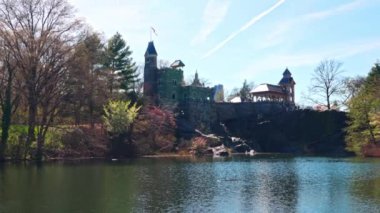 Central Park Manhattan 'daki gölün güneşli bahar günü manzarası, Belvedere Kalesi' nin mavi gökyüzü ve beyaz bulutların önünde. - New York. ABD. 