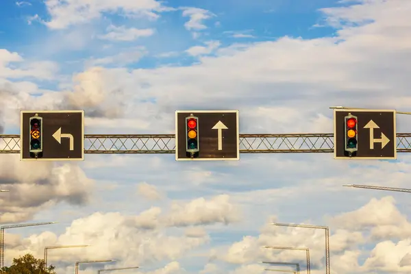 stock image Beautiful view of traffic lights with directional road signs for left turn, straight ahead, and right or straight under cloudy sky. Sweden.