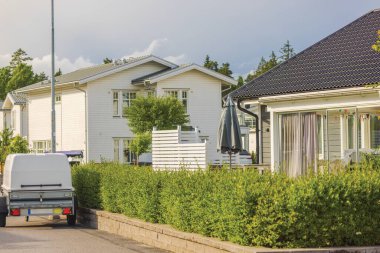 Avrupa 'da manzara tasarımlı, iki katlı modern ahşap villalar, caddeye park edilmiş bir araba römorku. İsveç.