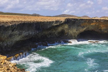 Rocky shore of Arikok National Park in Aruba, where Caribbean waves meet a desert landscape. clipart