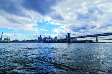 East River 'ın üzerindeki Brooklyn Köprüsü manzarası şehrin silueti ve arka planda bulutlu gökyüzü. - New York. ABD.