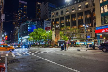 Gece New York 'ta sokak manzarası. Binalar, ağaçlar ve sokak lambaları altında arabalar. - New York. ABD.