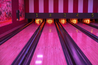 Turuncu-kırmızı gece ışıklarıyla aydınlatılan beş lobutlu bowling sahası..