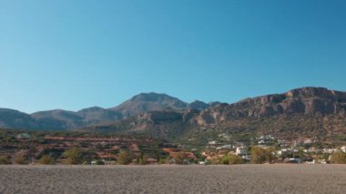 Açık mavi gökyüzü olan güneşli bir günde Girit 'teki dağların panoramik manzarası ve Akdeniz kıyısındaki üste villalar. Yunanistan.