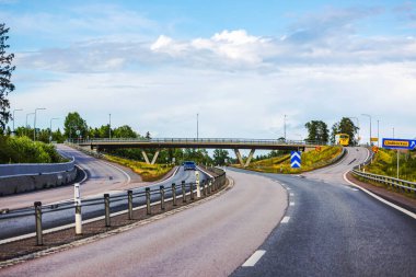 Köprü ile manzaralı otoyol kavşağı, seyrek trafik ve otobüslerle modern ulaşımın akışını gösteriyor. 